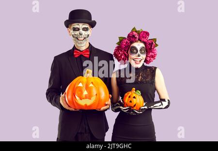 Fröhliche fröhliche Mann und Frau in Halloween Kostümen mit Pumkins in den Händen. Stockfoto