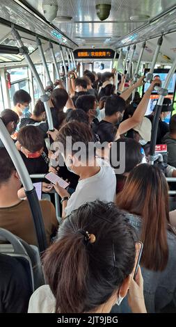 Eine vertikale Aufnahme von Menschen mit Masken, die während der Coronavirus-Pandemie auf überfüllten Bussen pendeln Stockfoto