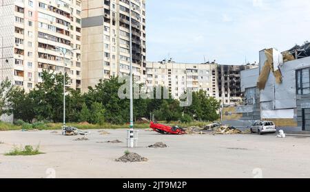 KHARKIV, UKRAINE - 30. Jul. 2022: Wohnhochhäuser mit Spuren von Bränden und Kratern durch Granatexplosionen. Umgedrehter Wagen. Die Straßen von Charkiw während des Krieges. Stockfoto