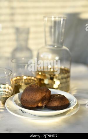 Eine vertikale Nahaufnahme von köstlichen Keksen, serviert mit Tassen Saft auf dem Tisch Stockfoto