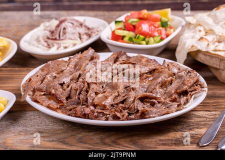 Fleisch Döner Kebab auf dem Teller. Türkischer Fleischspieß auf Holzhintergrund. Traditionelle türkische Küche. Nahaufnahme Stockfoto