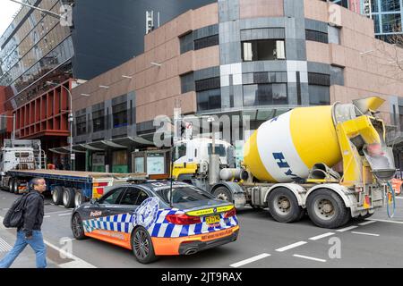 Polizeiauto und Transportbetonwagen auf der Bathurst Street im Stadtzentrum von Sydney, NSW, Australien Stockfoto