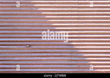 Rostige Metall gestreifte Wand der Garage, grunge Textur und Muster, schmutzige strukturierte Stahl lackiert Tür mit abblätternder Farbe, Hintergrund, abstrakter Horizont Stockfoto