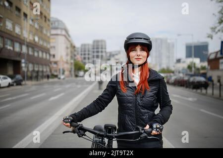 Porträt einer Geschäftsfrau, die Pendlerin auf dem Weg zur Arbeit mit einem Fahrrad, einem nachhaltigen Lifestyle-Konzept. Stockfoto