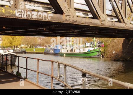 Eine Ansicht der Lastkähne im Kanalbecken von Ely, Cambridgshire, England, zeigt die Eisenbahnbrücke, die den Kanal überquert Stockfoto