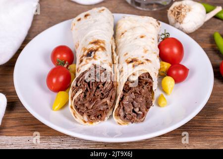 Döner Kebab Einwickeln. Fleisch Döner Kebab auf Holzhintergrund. Traditionelle türkische Küche. Nahaufnahme. Lokaler Name durum et doner Stockfoto