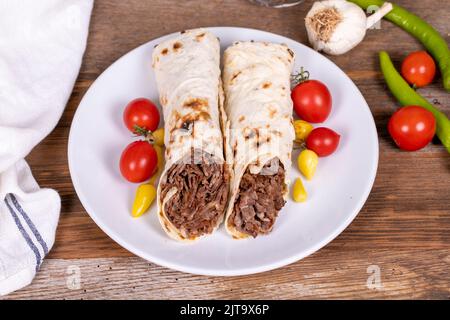 Döner Kebab Einwickeln. Fleisch Döner Kebab auf Holzhintergrund. Traditionelle türkische Küche. Nahaufnahme. Lokaler Name durum et doner Stockfoto