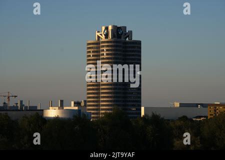 10. August 2022, Bayern, München: Blick vom Olympiapark in Richtung des von der Abendsonne beleuchteten BMW-Wolkenkratzers. Das Gebäude auf dem Petuelring, auch bekannt als „BMW Four Cylinder“, ist über 100 Meter hoch und wurde für die Olympischen Sommerspiele 1972 fertiggestellt. Foto: Soeren Sache/dpa Stockfoto