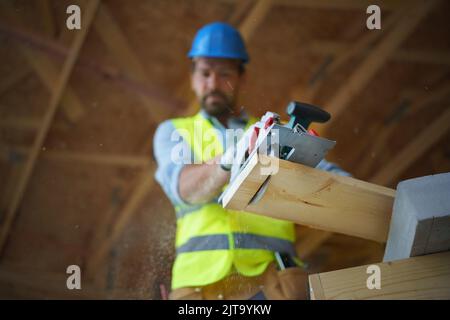 Low-Angle-Ansicht des Handwerkers mit Kreissäge auf Holzbaustelle arbeiten, diy umweltfreundliche Häuser Konzept. Stockfoto