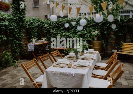 Festliche Hochzeitstische mit Blumen bei einem kleinen Empfang im Garten im Sommer. Stockfoto