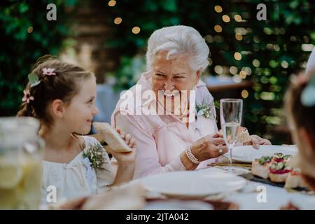 Hochzeitsgäste sitzen am Tisch, essen und trinken an der Rezeption draußen im Hinterhof. Stockfoto