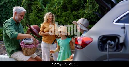 Familie mit kleinen Kindern, die das Auto laden und auf das Auto warten, bevor sie zum Picknick gehen. Stockfoto