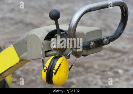 Gehörschutz hängt an der Vibrationsplatte - Lärmschutz auf der Baustelle Stockfoto