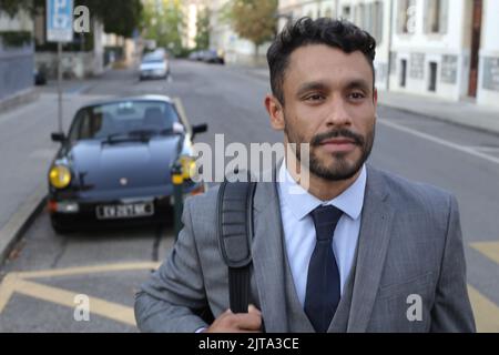Geschäftsmann mit coolen Sportwagen im Hintergrund Stockfoto