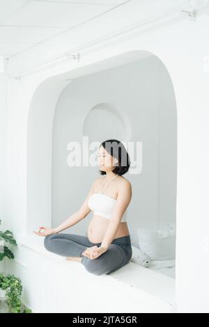 Schwangere junge Frau macht Yoga zu Hause Stockfoto