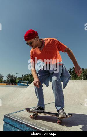 Junger und stilvoller Skater, der im Skatepark von der Rampe springt Stockfoto