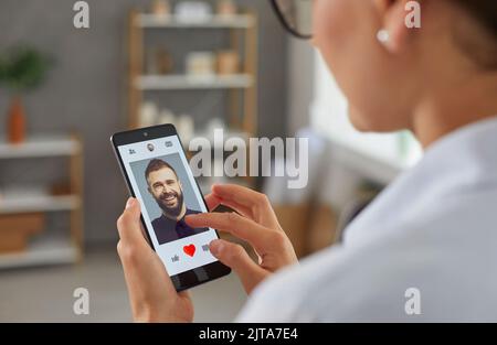 Die Frau wird ein Foto wie dem Mann in der mobilen Dating-App auf dem Smartphone geben. Stockfoto