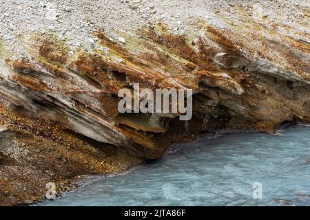 Hydrothermale mineralisierte Strömung, die am Hang des Vulkans zwischen den Ufern der Vulkanasche und des Tephras fließt Stockfoto