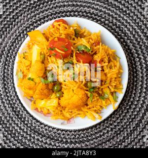 Indisch-vegetarisch gebratener Reis auf dem Teller mit Karotte, Frühlingszwiebeln, grünen Erbsen, Kolliflower Stockfoto