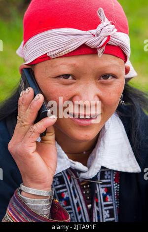 In der nördlichen Stadt Sapa benutzt die Frau des Stammes der Roten Dao, Vietnam, ihr Mobiltelefon. Stockfoto