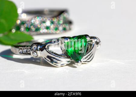 Claddagh Ring mit grünem Smaragd. Traditioneller irischer Ring in Form von zwei Händen, der einen herzförmigen grünen Edelstein hält. Symbol für Liebe, Treue und Frie Stockfoto