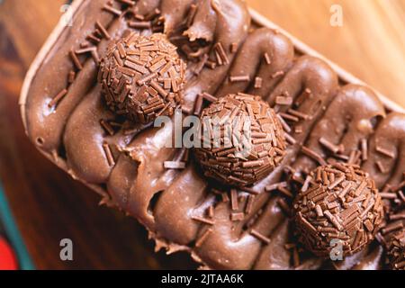 Kuchen namens Brigadeiro Caseirhiro. Schokoladenkuchen mit Schokoladenfrosting und Brigadierern zum Dekorieren. Süßwaren, Dessert. Stockfoto