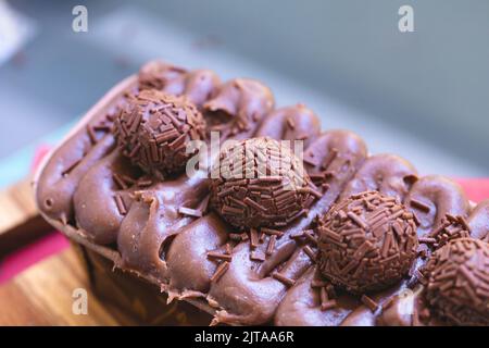 Kuchen namens Brigadeiro Caseirhiro. Schokoladenkuchen mit Schokoladenfrosting und Brigadierern zum Dekorieren. Süßwaren, Dessert. Stockfoto