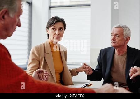Gruppe von Personen, die während der Psychotherapie die Hände im Kreis halten Stockfoto