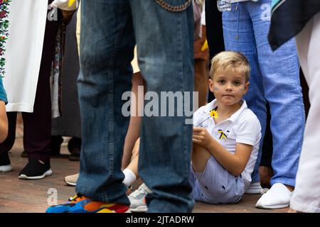 Washington, USA. 27. August 2022. Washington, DC - 27. August 2022: Ein Kind sitzt auf der Kundgebung mit einer Blume und ukrainischen Fahnen auf seinen Wangen. Ukrainer, Weißrussen, Georgier und andere versammelten sich auf dem Lafayette-Platz, um den Unabhängigkeitstag der Ukraine zu feiern, bevor sie zu einer kurzen Zeremonie zur Statue des ukrainischen Dichters Taras Schewtschenko marschierten. Die Versammlung war auch der 6-monatige Jahrestag der russischen Invasion in der Ukraine. (Foto von Kyle Anderson/Sipa USA) Quelle: SIPA USA/Alamy Live News Stockfoto