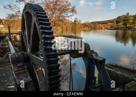 Schleusentor-Antriebsrad und Wehr auf dem Fluss Derwent, Teil des Wasserkraft-Systems, das einst die Baumwollmühlen in Belper, Derbyshire, Großbritannien, trieb Stockfoto