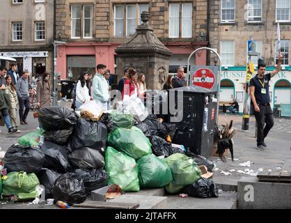 Edinburgh, Schottland, Großbritannien. 29.. August 2022. In der zweiten Woche streiken Müllmänner aus Edinburgh, und die Straßen der Stadt sind mit Abfall aus überlaufenen Mülltonnen bedeckt. Foto: Touristen auf einer Stadtrundfahrt passieren einen großen Haufen Müll auf dem Grassmarket. Iain Masterton/Alamy Live News Stockfoto