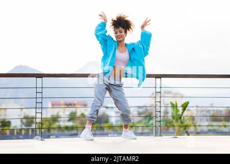 lateinamerikanische hispanische Frau, die bei Sonnenuntergang auf der Straße tanzt Stockfoto