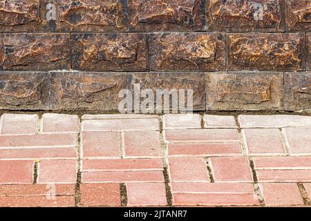 Textur einer Wand, die mit dekorativen Ziegelsteinen und Pflaster bedeckt ist. Abstrakter Hintergrund für Design. Stockfoto