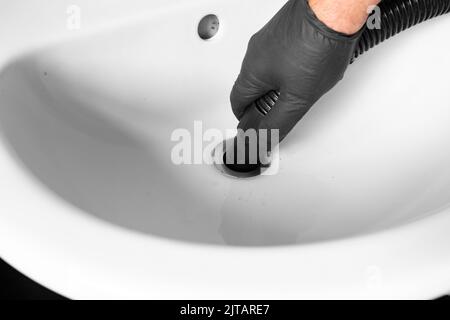 Mann entblockierte Rohre in einem Waschbecken mit einem staubsauger. Machen Sie es selbst Wartungskonzept Stockfoto