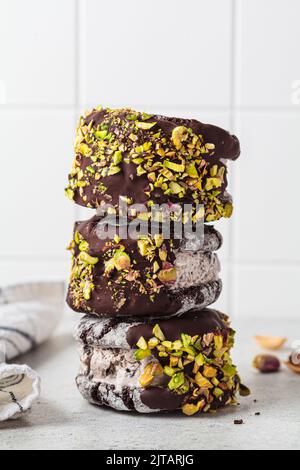 Stapel von Schokoladenkeks-Eiscreme-Sandwiches mit dunkler Schokolade und Pistazien, Nahaufnahme. Stockfoto