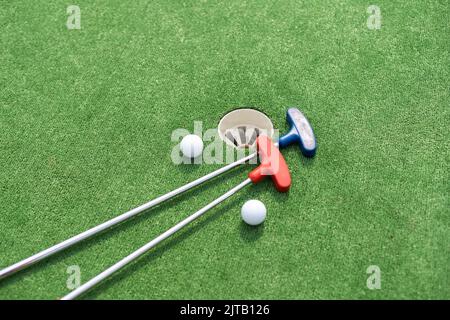 Mini-Golfschläger und Kugeln in verschiedenen Farben auf Kunstrasen gelegt Stockfoto