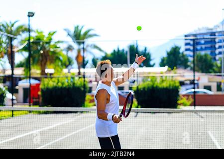 Älterer kaukasischer Mann, der auf dem Tennisplatz Tennis spielt und tagsüber im Freien an der frischen Luft Tennisschläger hält Stockfoto