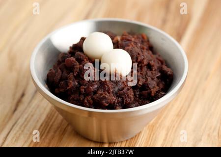 Koreanischer Haferbrei mit roten Bohnen und Reiskuchen oder Patjuk. Auf Holztisch Stockfoto