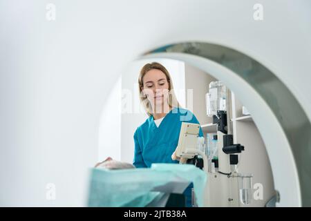 Die Ärztin steht in der Nähe des Patienten im Tomographieraum Stockfoto