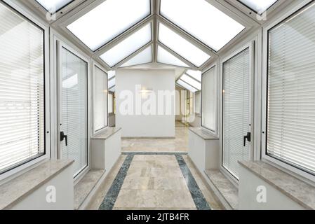 Durchgang mit Decken und Wänden aus Glas und Aluminium und Marmorböden mit grünen Kanten Stockfoto