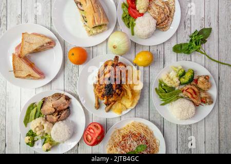 Set von gesunden Gerichten mit viel gedünstetem Gemüse, gedämpftem Reis, gegrilltem Huhn, Schinken- und Käsesandwich, frischem Basilikum und gegrilltem c Stockfoto