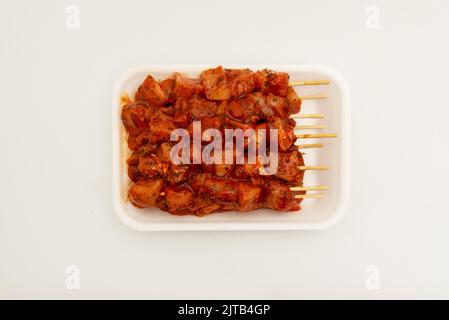 Marinierte maurische Hähnchenspieße mit Holzstäben auf einem weißen Polystyrol-Tablett Stockfoto