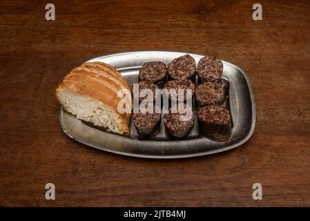 Spanische Tapa mit gehacktem schwarzen Pudding, bereit, mit Dorfbrotscheiben auf einem Metalltablett zu braten Stockfoto