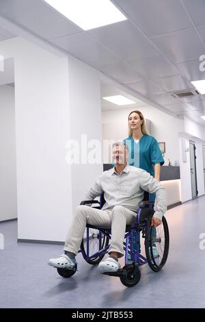 Der Arzt in einem blauen Anzug trägt einen Patienten auf dem Flur Stockfoto