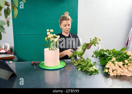 Frau Floristin Herstellung Blume Komposition während der Arbeit in Blumenladen Stockfoto