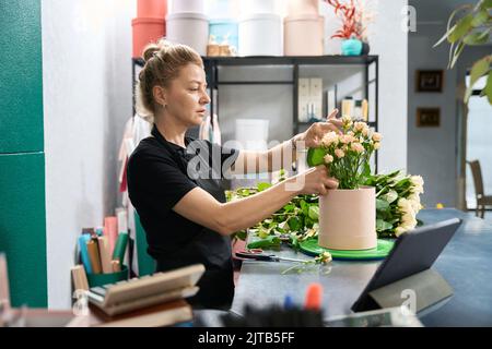 Schöne weibliche Floristin schafft einen Strauß in einer runden Box Stockfoto