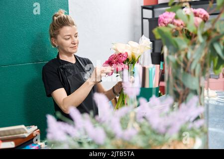 Frau Floristin macht Zusammensetzung aus Callas, Hortensien und Pfingstrosen Stockfoto
