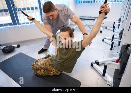 Physiotherapeut hilft dem Patienten, sich von einer Rückenmarksverletzung zu erholen Stockfoto