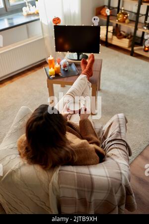 Frau schaut an halloween Fernsehen und trinkt Kakao Stockfoto