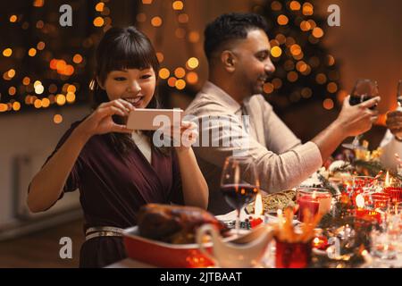 Fröhliche Frau, die beim weihnachtsessen Essen fotografierte Stockfoto